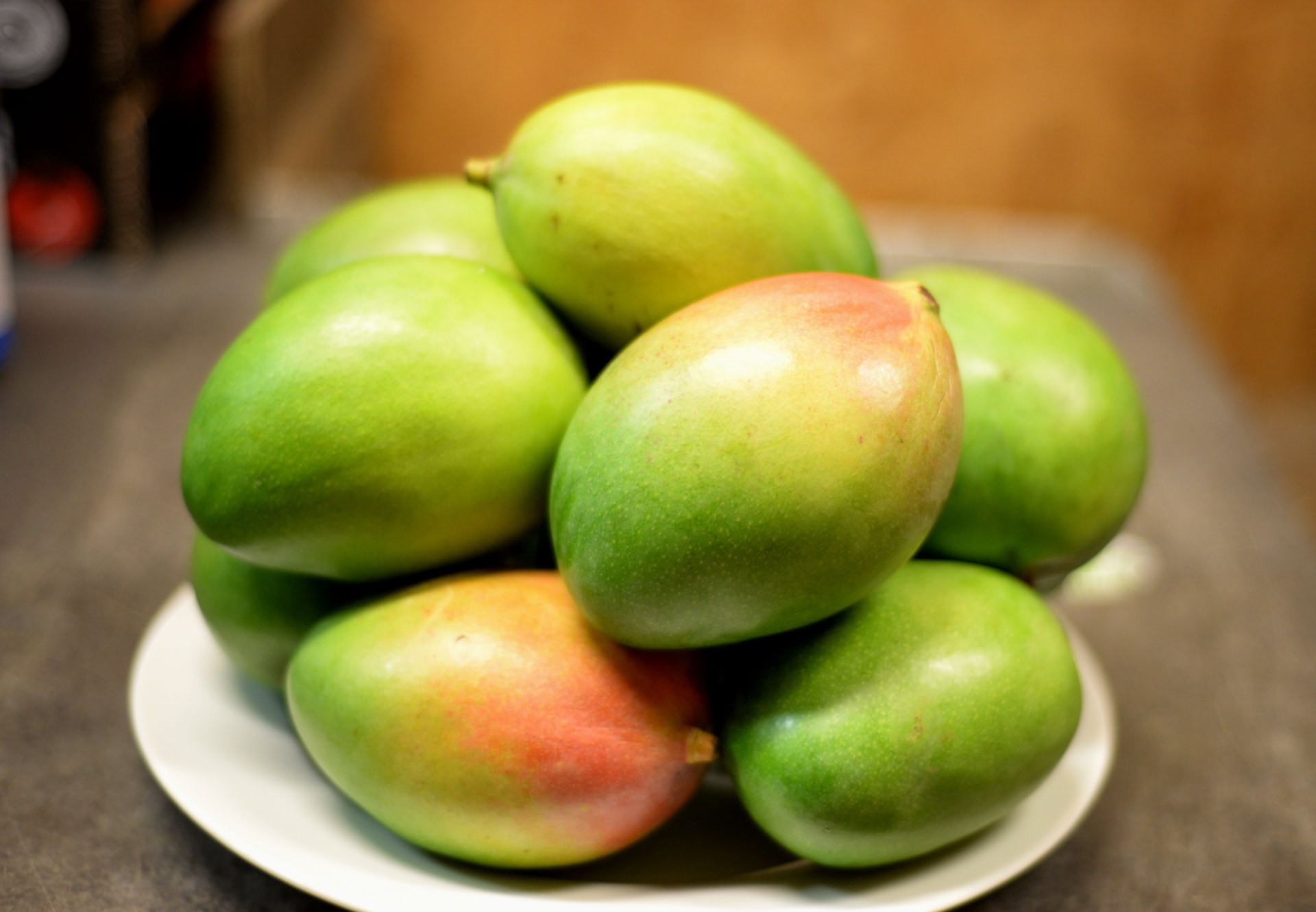 A plate piled high with green and red-blushed mangoes. Photo: A Little Bit of Mercy by Lisa Ford